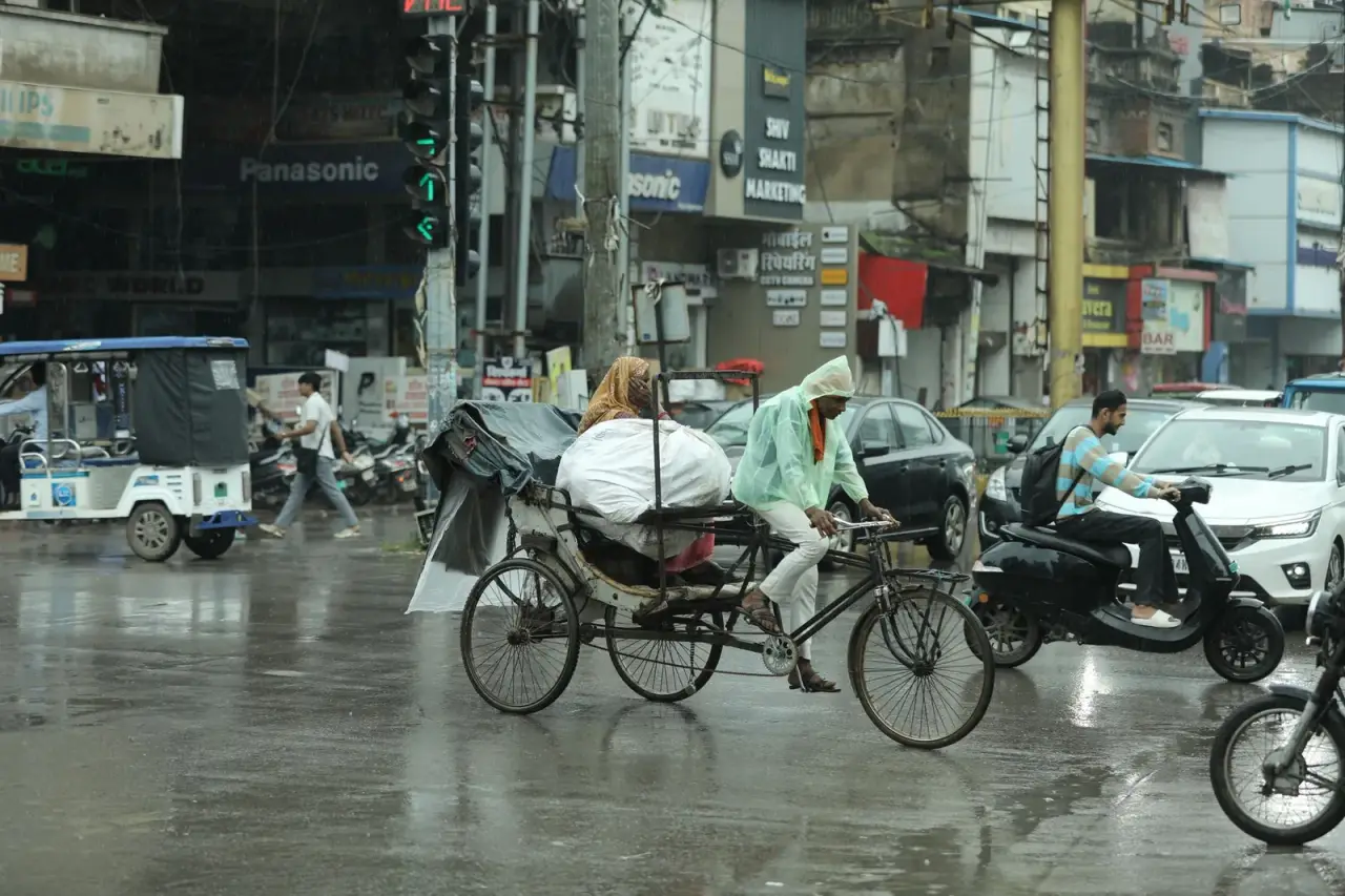 Rickshaws and traffic on a Raipur street in the rain