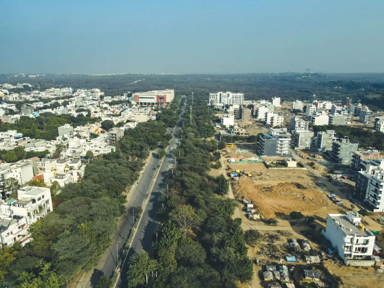 Aerial view of Gurugram with a wide road through green cover
